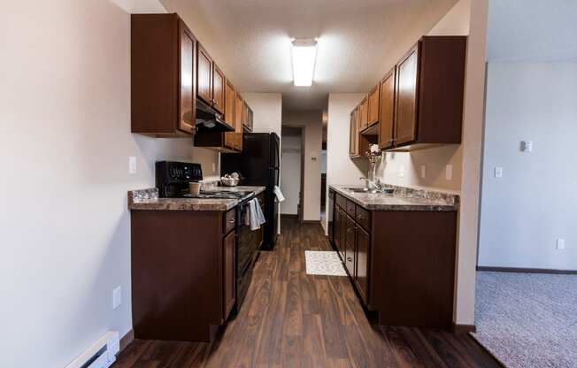 Grand Forks, ND Library Lane Apartments a kitchen with brown cabinets and a wood floor