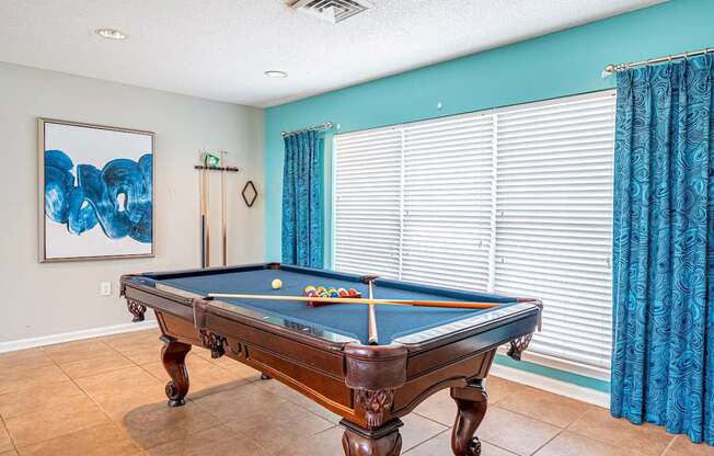 A pool table in a room with a blue wall.