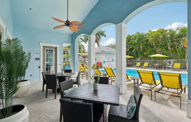 A patio with a table and chairs overlooking a pool.