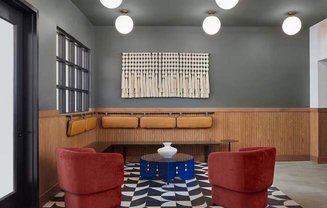 A black and white checkered floor in a room with a wooden bench and red chairs.