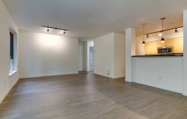 A spacious room with wooden floors and a bar area with a microwave.