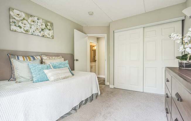 A bedroom with a bed, dresser and a painting on the wall.