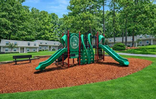 A playground with a green slide and a red and green play structure.