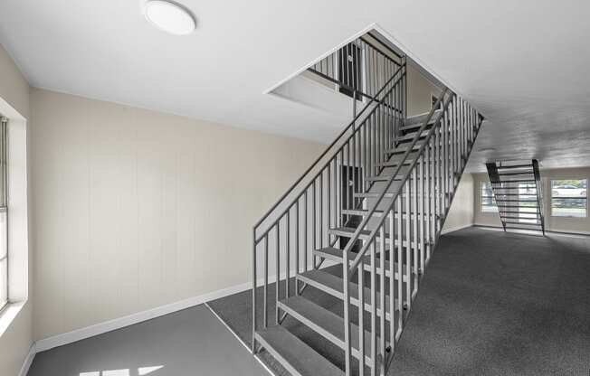 the stairwell of a home with grey carpeting and stainless steel railing at Brookside Apartments, Hewitt, Texas