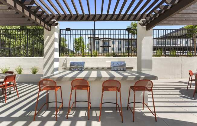 a patio with a bar with chairs and a table