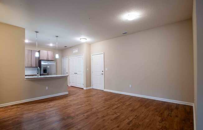 an empty living room and kitchen with wood flooring