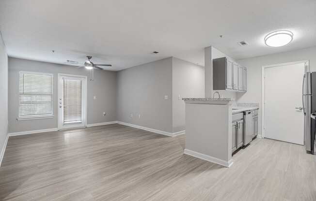 an empty living room and kitchen with a refrigerator and a sink