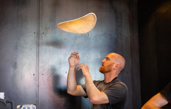 Image of man tossing pizza dough