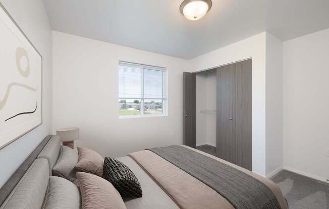 A bedroom with a large bed and a window overlooking a green area.