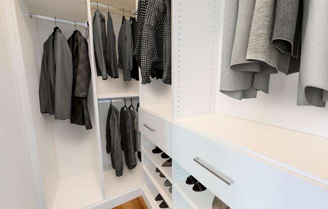 a walk in closet with white cabinets and drawers