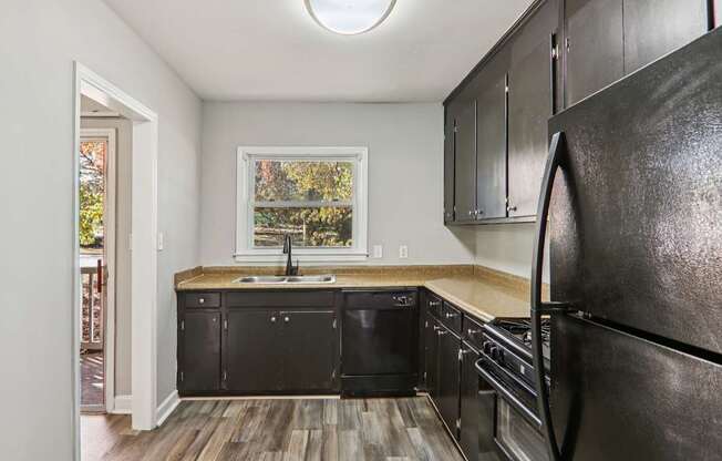A kitchen with black cabinets and a black fridge.
