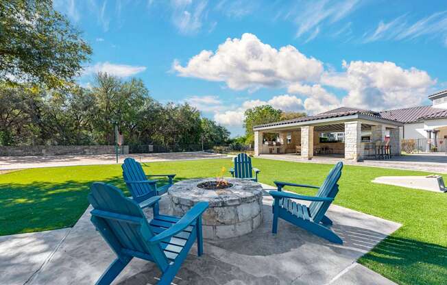 A patio with blue chairs and a fire pit.