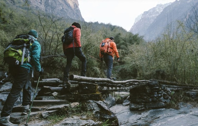 three people with backpacks hiking up a trail in the mountains