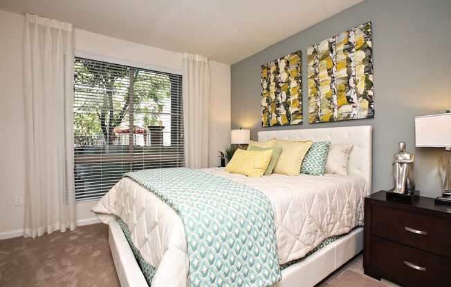 A bedroom with a large bed and a window with blinds. at The Kitt at Warner Center Apartments, Woodland Hills, California