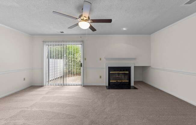 living room with a fireplace, ceiling fan, and large window at Rosewood at Colony Square, Rocky Mount, North Carolina