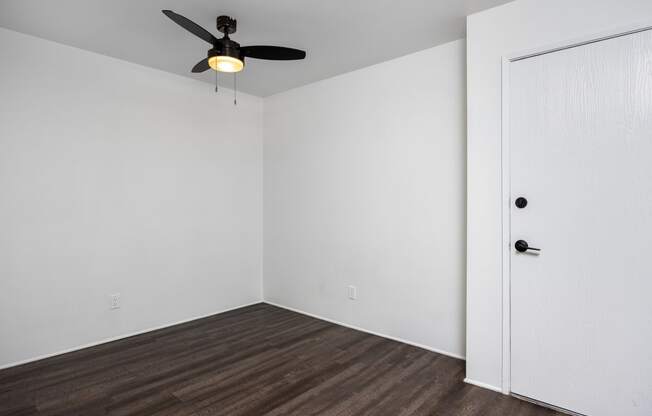 an empty room with white walls and a ceiling fan
