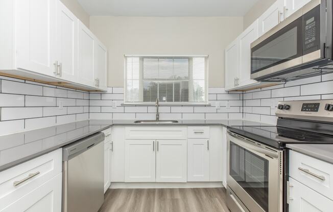 a kitchen with white cabinets and black appliances and a window