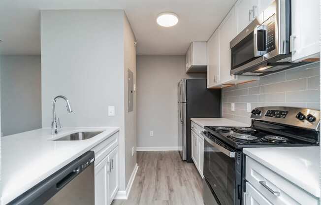 an empty kitchen with white cabinets and stainless steel appliances