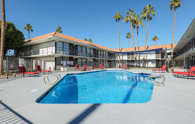A swimming pool in front of a building with palm trees.