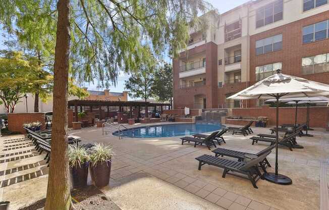 A pool area with sun loungers and a tree at Prairie Crossing, Farmers Branch, 75244