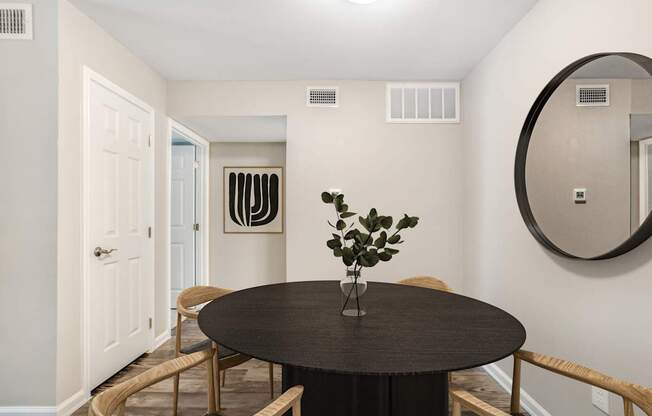 Pet-Friendly Apartments in Houston, TX – Artisan West – A round table with a vase of flowers on it sits in a room with a mirror and a door.