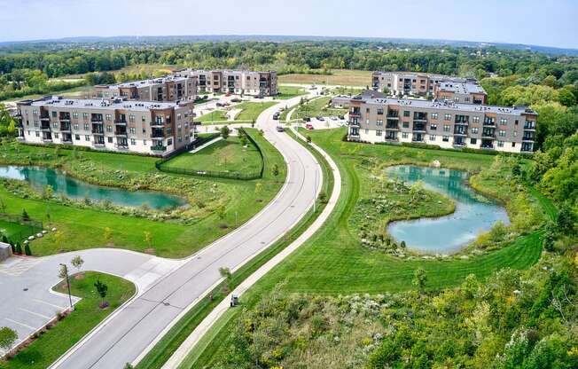 an aerial view of multiple apartment buildings with lakes and a road at Statesman Apartments, Franklin, 53132