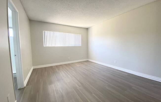 an empty living room with wooden floors and a window