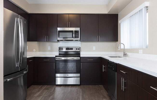 Apartments for Rent in Palo Alto, California - Tan Plaza - Modern Kitchen with Stainless Steel Appliances, White Countertops, Dark Wood-Style Cabinetry, Overhead Lighting, Plank Wood Flooring, and Win