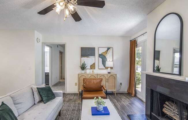 A living room with a grey couch, a fireplace, and a ceiling fan.