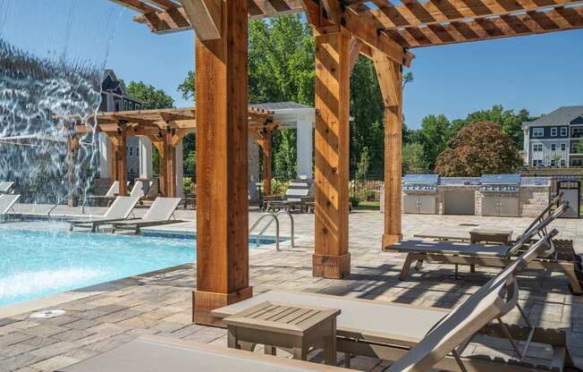 A poolside area with a waterfall and lounge chairs at The Ashton at East Park Apartments, Georgia