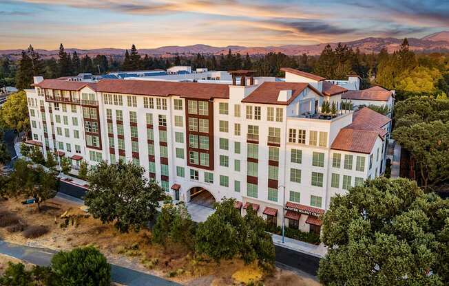 Sunset view of a Mediterranean-style apartment residence surrounded by rolling hills and natural beauty
