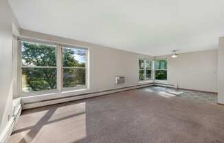 an empty living room with large windows and a carpet