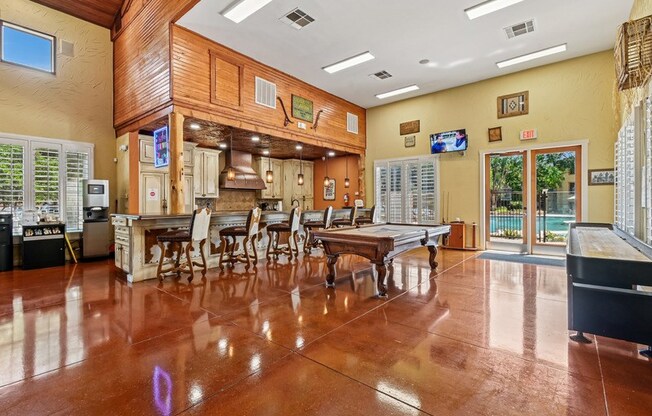 A large room with a wooden floor and a bar area. at The Canyons Apartments, Fort Worth