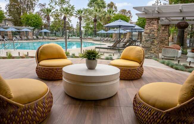 a lounge area with chairs and a table near a pool