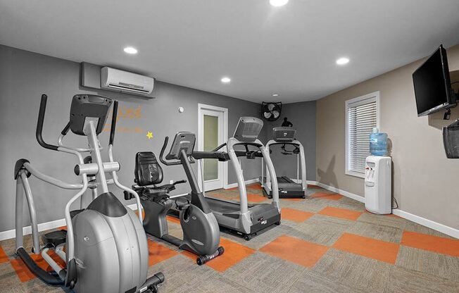 a gym with several exercise bikes and a tv