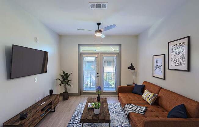 A living room with a brown couch and a flat screen TV mounted on the wall.