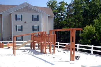 A playground with a slide and swings in front of a house.at Summerland Heights, Woodbridge Virginia  