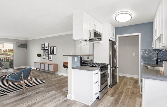 Kitchen with blue tile backsplash and view of adjacent living room.