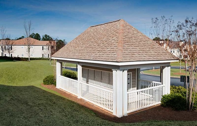 a small white gazebo with a wooden fence