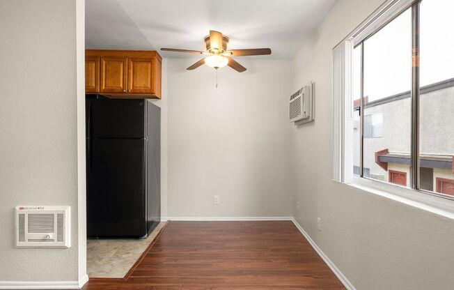 an empty room with a ceiling fan and a refrigerator