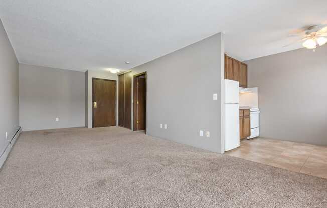 an empty living room with a kitchen and a ceiling fan. Roseville, MN Rosedale Estates