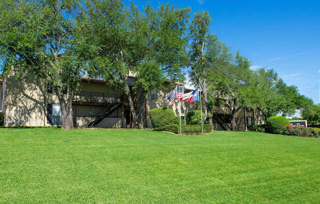 View from the loop of the property with lush grass, flags flying high, and exterior of building in the background