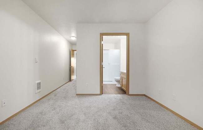A carpeted hallway with a doorway leading to a bathroom.