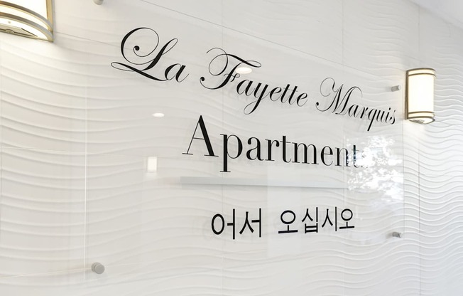 A sign that says La Fayette Marquis Apartment in cursive font.