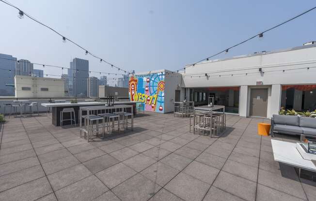 a rooftop patio with tables and chairs and a mural on the side of a building