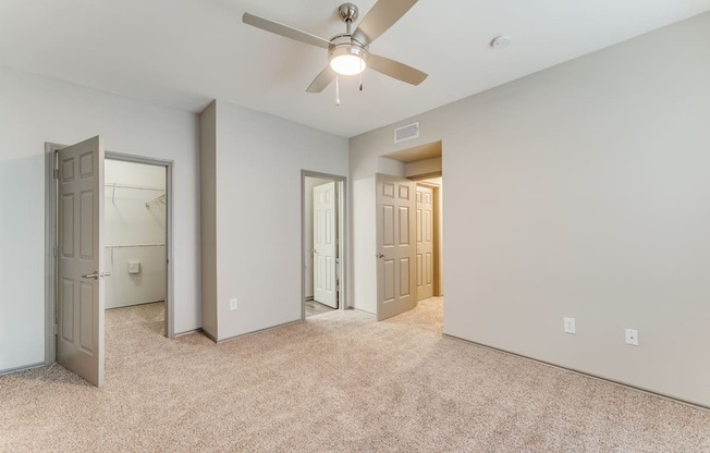 A room with a ceiling fan and carpeted floor.