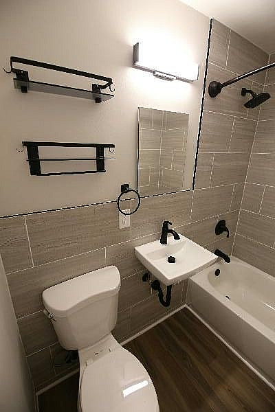Modern bathroom featuring sleek fixtures, elegant grey tiles, and contemporary shelving.