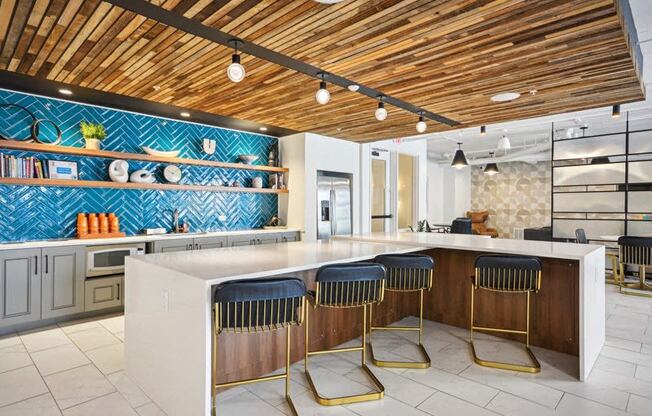 a kitchen with a counter and three chairs at Link Apartments® 4th Street, Winston-Salem