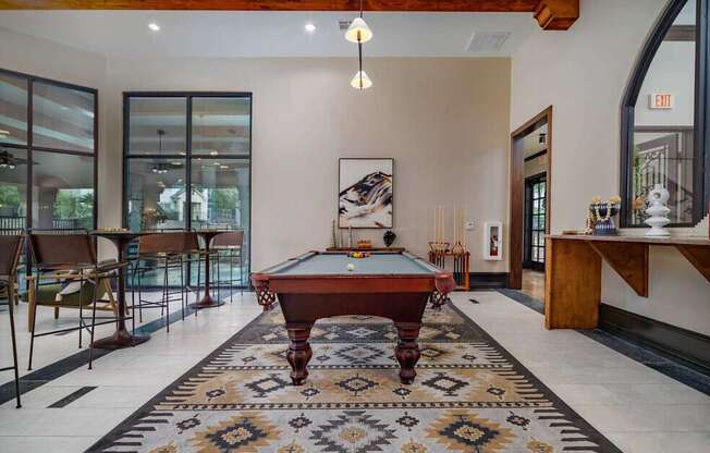 A pool table is in the middle of a room with a rug on the floor.