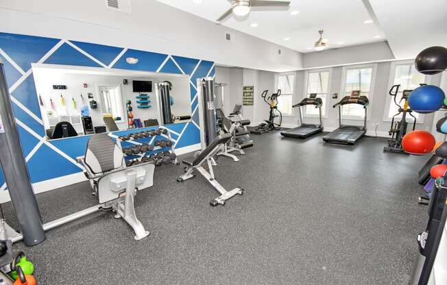 a spacious fitness room with cardio equipment and weights